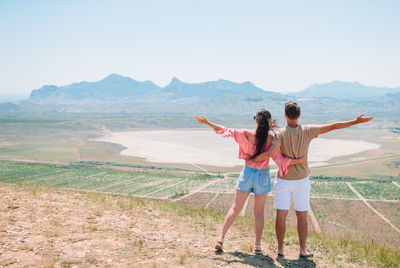 Rear view of women standing on mountain against sky