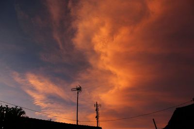 Low angle view of silhouette electricity pylon against sky during sunset