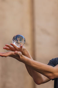 Close-up of hand holding crystal ball with reflection of building