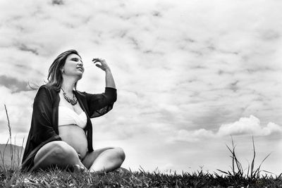 Full length of young woman in grass against sky
