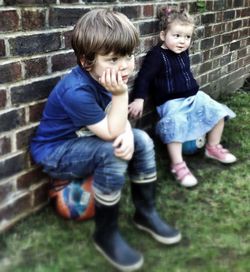 Siblings standing against wall