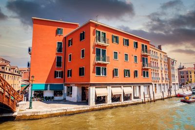 Canal amidst buildings against sky during sunset