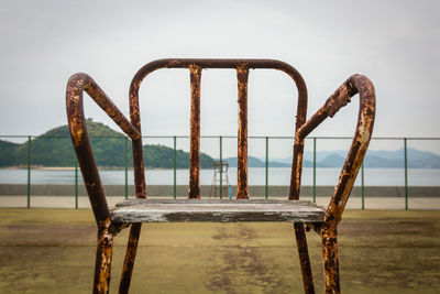 Close-up of rusty metal railing against sky