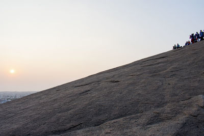 People on mountain against clear sky during sunset