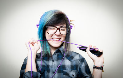 Close-up of young woman wearing eyeglasses against white background