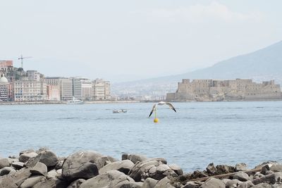 Sea by city against sky