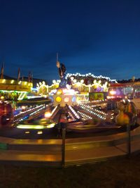 Illuminated carousel against clear sky at night