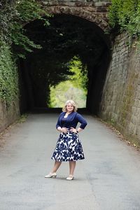 Full length portrait of woman standing against wall