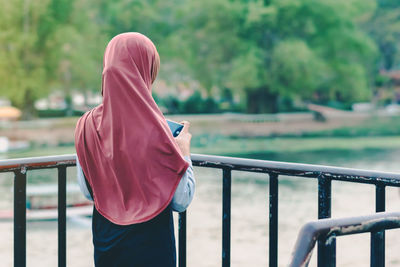 Rear view of woman standing against railing