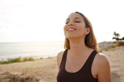 Relaxed happy young woman breathing fresh air on the beach
