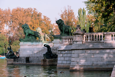 Statue by lake against trees