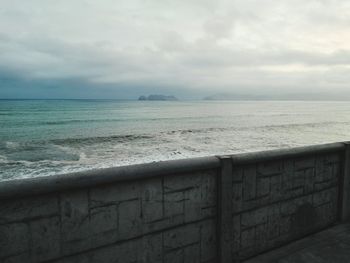 Scenic view of sea against cloudy sky seen from pier