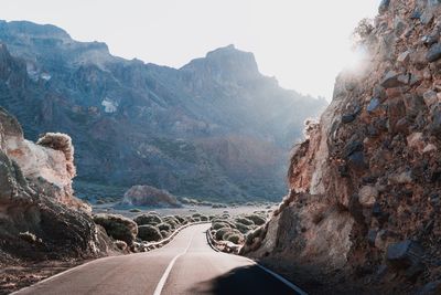 Road leading towards mountains against sky