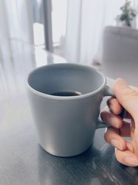 Close-up of hand holding coffee cup on table