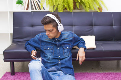 Young teenager with mobile phone and headphones at home