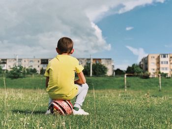 Rear view of boy sitting on soccer ball