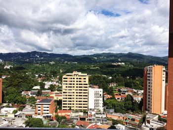 View of cityscape against cloudy sky