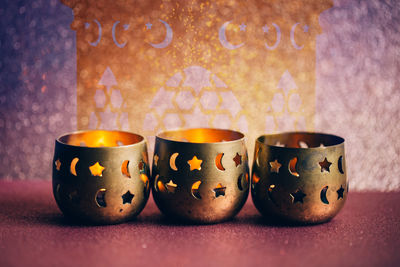 Close-up of illuminated candles on table against wall
