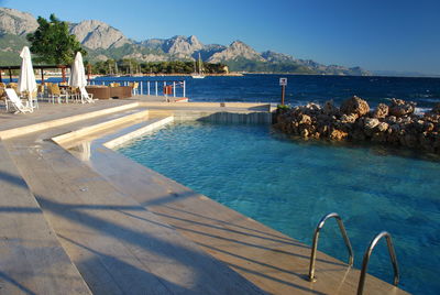Scenic view of swimming pool by sea against clear sky