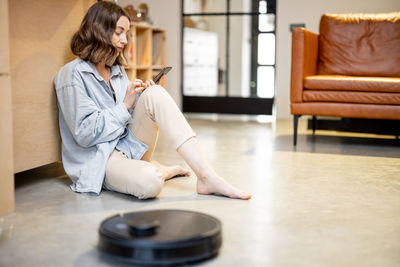 Woman using mobile phone while sitting on floor at home