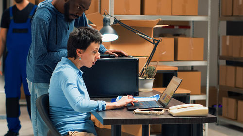 Rear view of man using laptop at office