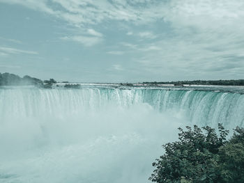 Scenic view of waterfall against sky