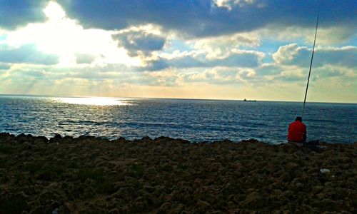 View of calm beach against cloudy sky