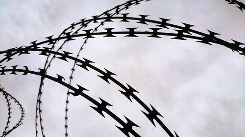 Low angle view of barbed wire against sky