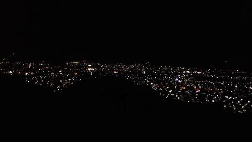 High angle view of illuminated city buildings against clear sky at night