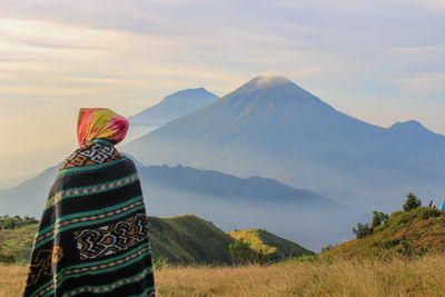 Rear view of person wearing shawl standing against mountain range