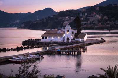 Scenic view of buildings by bay against sky during sunset