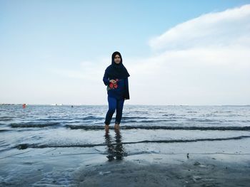 Portrait of young woman standing in sea