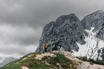 Woman standing on viewpoint in mountains under gray sky in winter