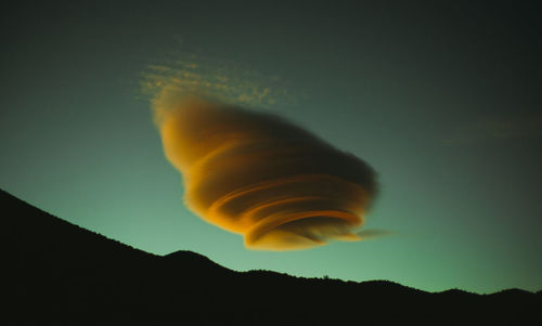 Orange surreal cloud over mountains in desert landscape during monsoon season