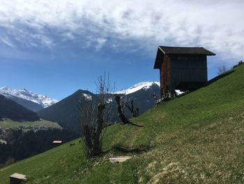 Scenic view of cottage by mountain against sky