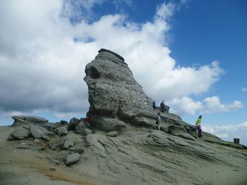 Low angle view of rocks against cloudy sky
