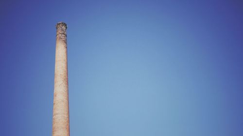 Low angle view of smoke stack against blue sky