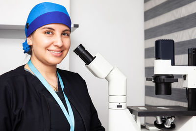 Beautiful young female scientist in the laboratory next to an inverted microscope