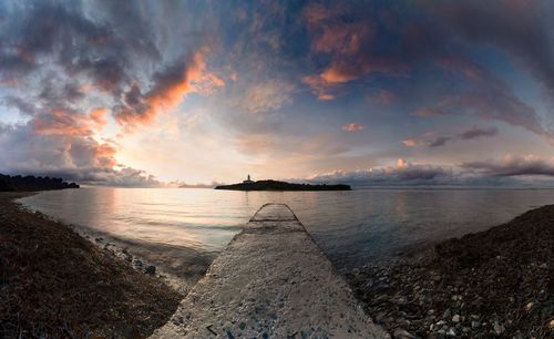 Scenic view of sea against dramatic sky during sunset