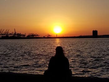 Silhouette woman looking at sea against sky during sunset