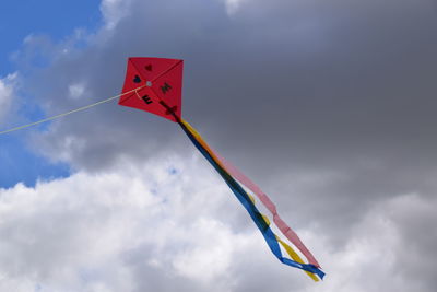 Low angle view of kite flying against cloudy sky