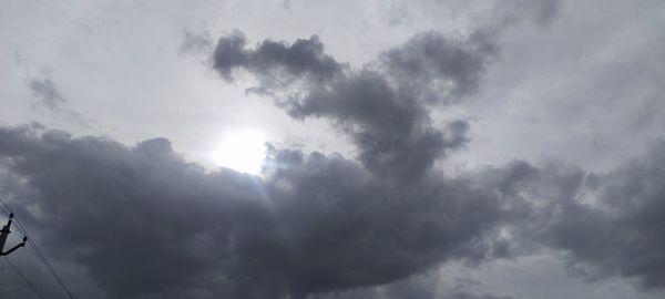 Low angle view of sunlight streaming through clouds