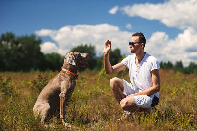 Young man with dog sitting on field