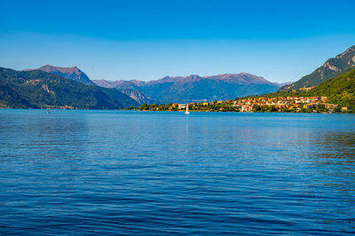 The town of mandello del lario, on lake como, with the mountains in the background, on a summer day.