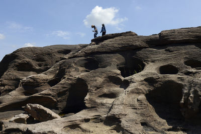 Low angle view of two people walking on rocky beach