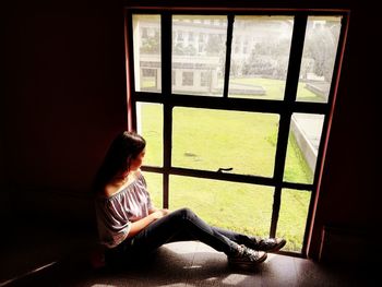 Woman looking through window at home