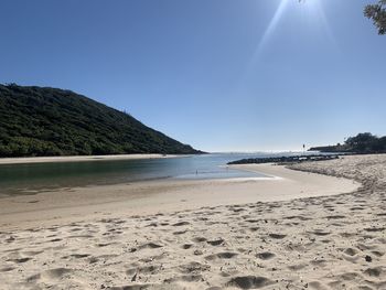 Scenic view of beach against clear blue sky