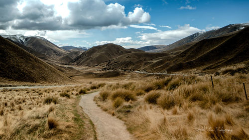 Scenic view of road by mountains against sky