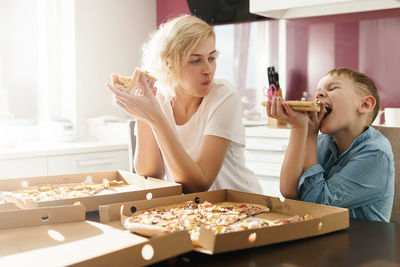 Mother and son eating pizza at home