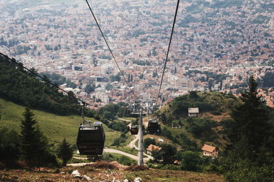 Overhead cable cars against buildings and trees in city